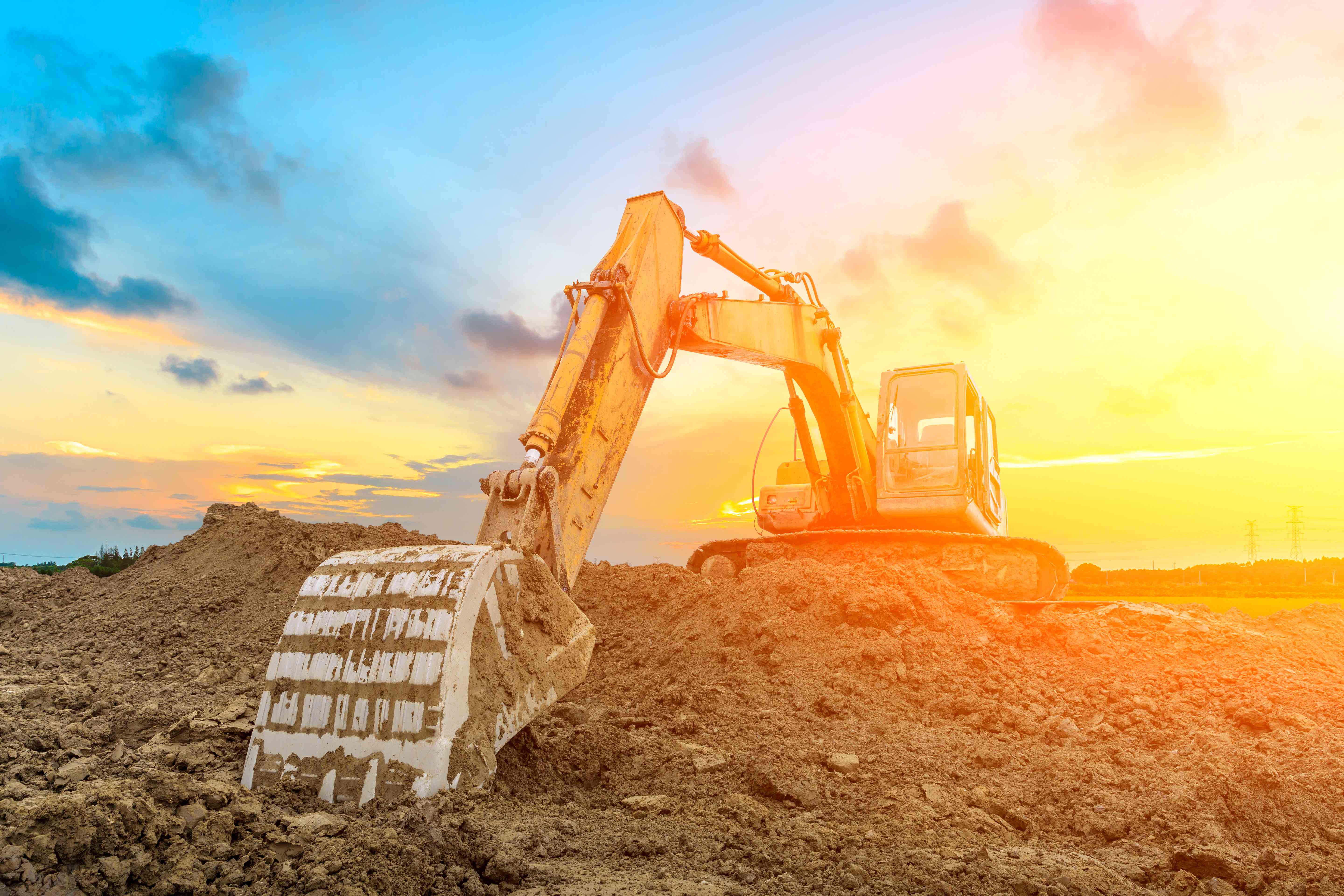construction digger pushing dirt with sunset in background