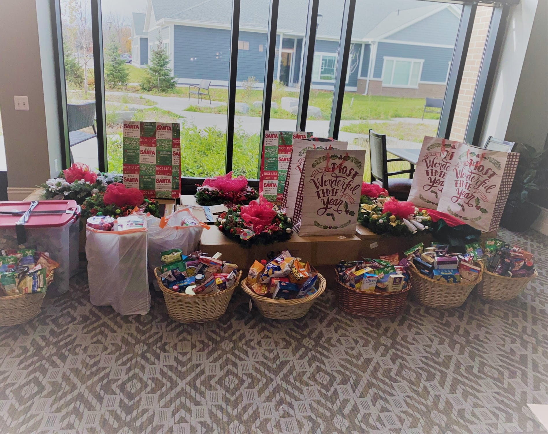 Christmas bags and baskets filled with gifts sitting on a table and the floor.