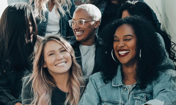 a diverse group of women sitting on stairs outside talking and smiling