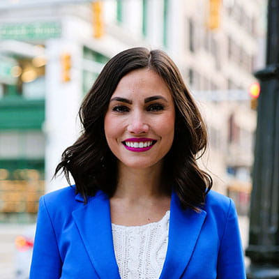 Maria outside smiling wearing a blue blazer and white shirt