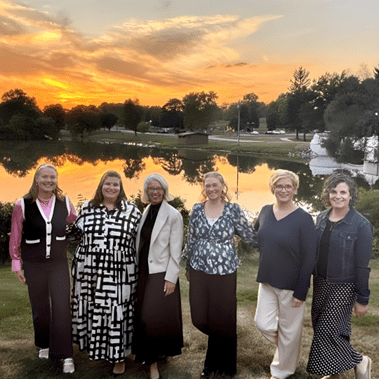 Menopause event panel standing outside smiling with a backdrop of water and sunset