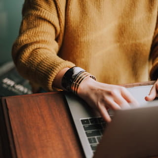 a person sitting at a desk typing on a laptop keyboard