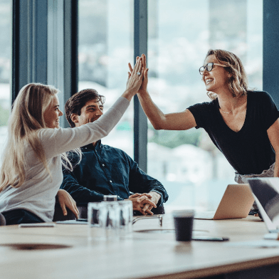 Photograph of employees in an office high-fiving