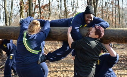 MYCA women help each other climb over big tree branch