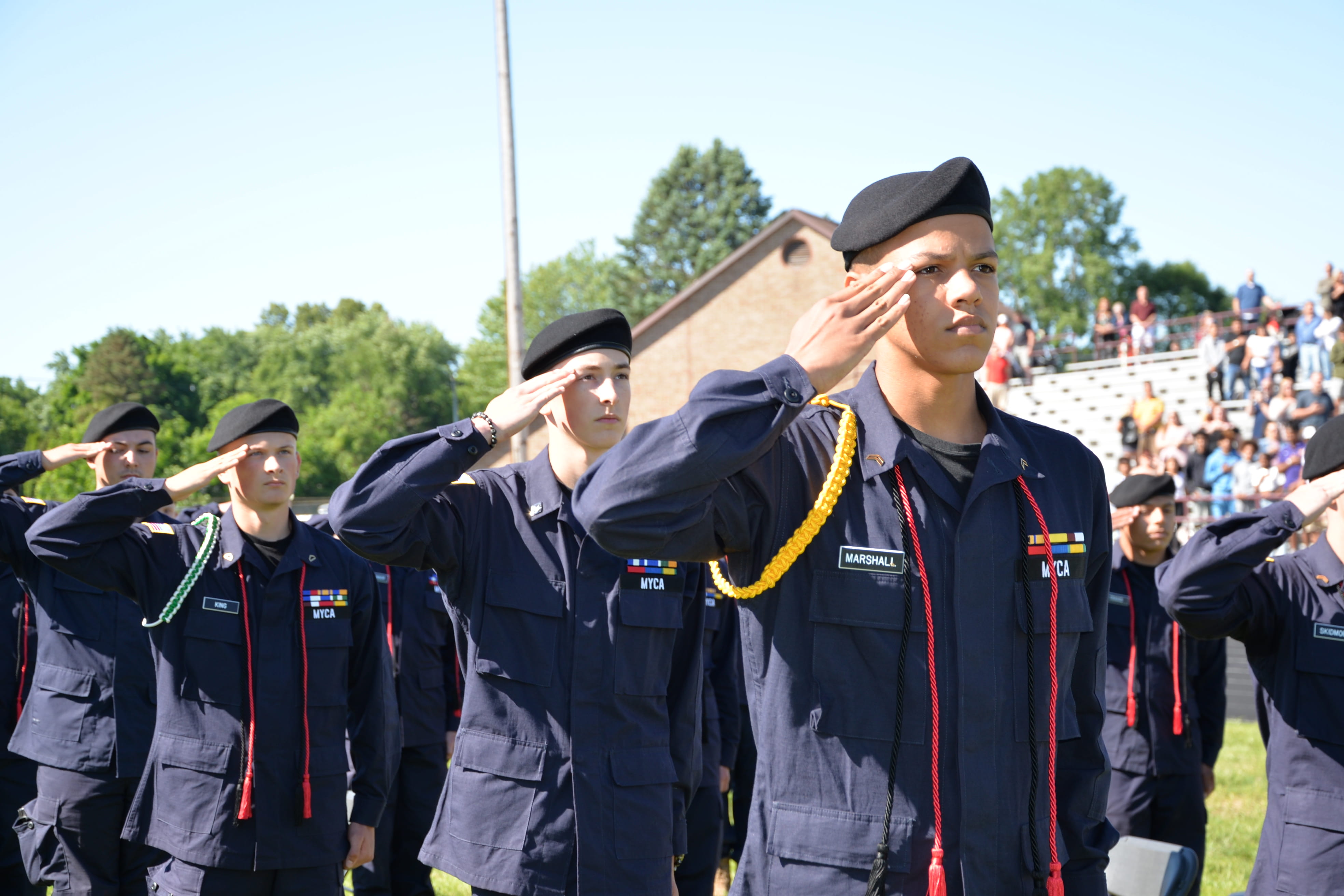 Male cadets in line, outdoors, soluting