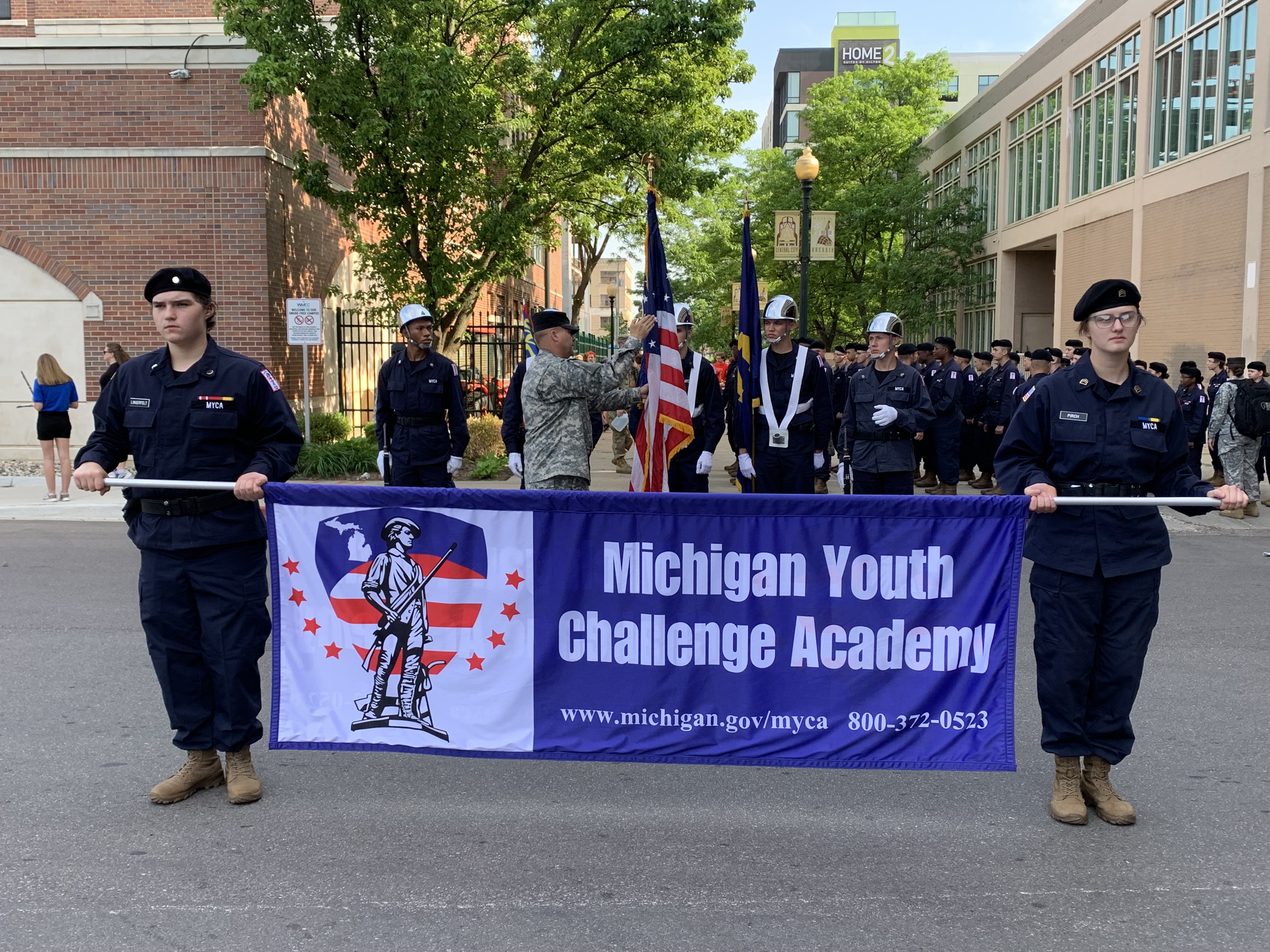 Cadets in uniform carrying blue banner that reads Michigan Youth Challenge Academy