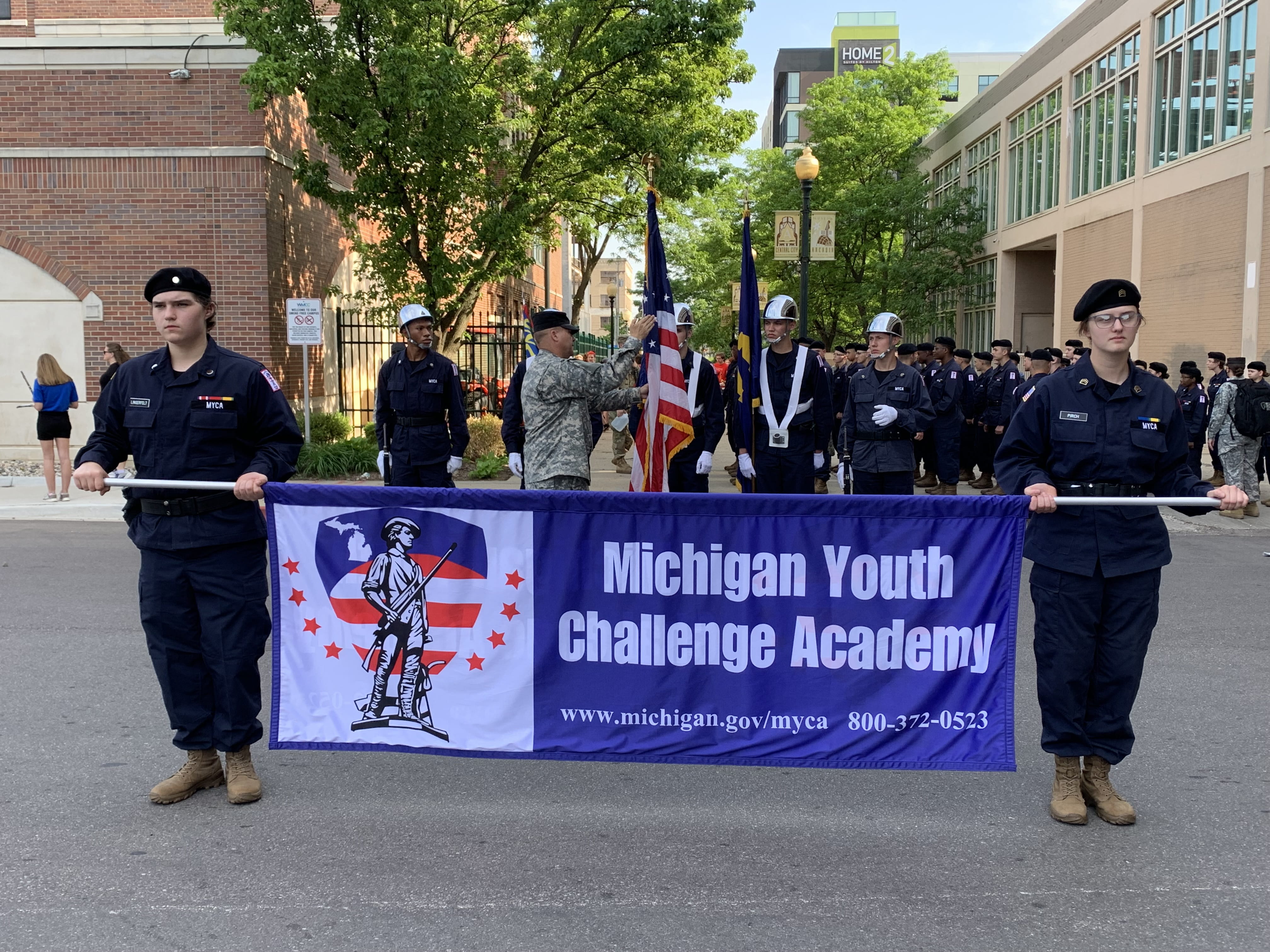 Cadets in uniform carrying blue banner that reads Michigan Youth Challenge Academy
