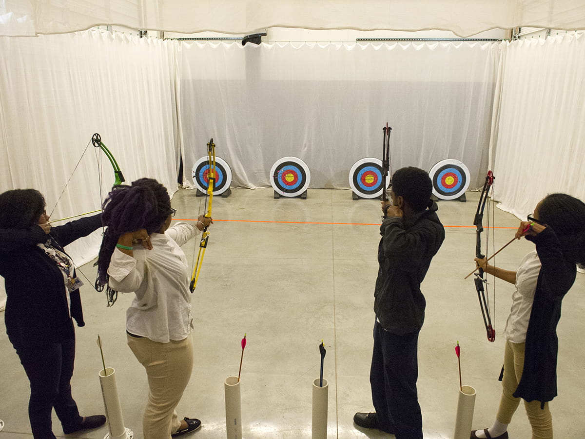 Four youngsters shooting bows and arrows at targets