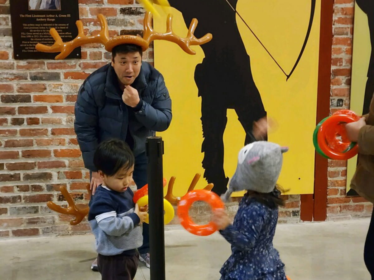 adult in reindeer antlers playing game with two small children