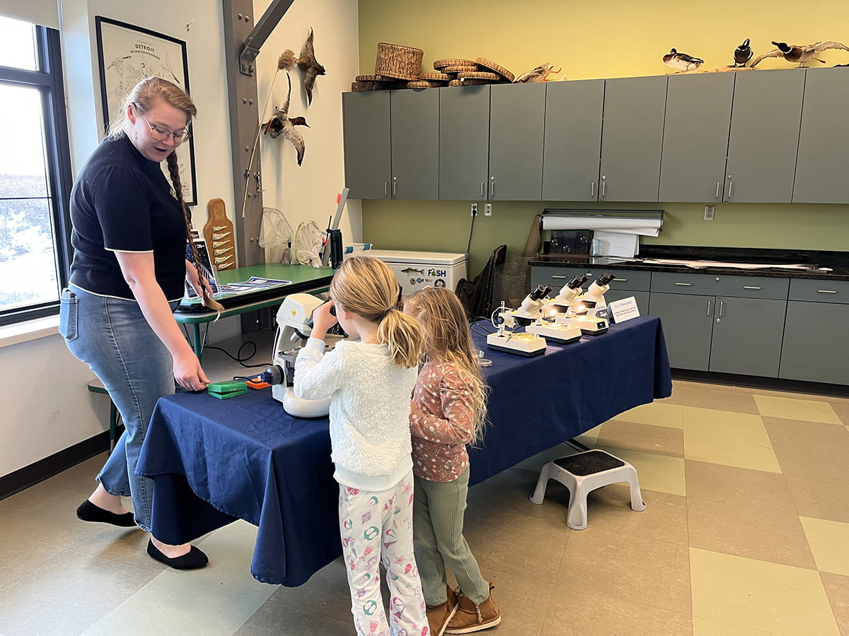 two children look through a microscope on a display table