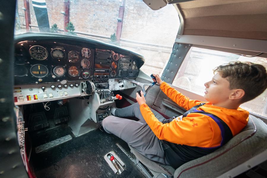 boy sits at controls of OAC airplane