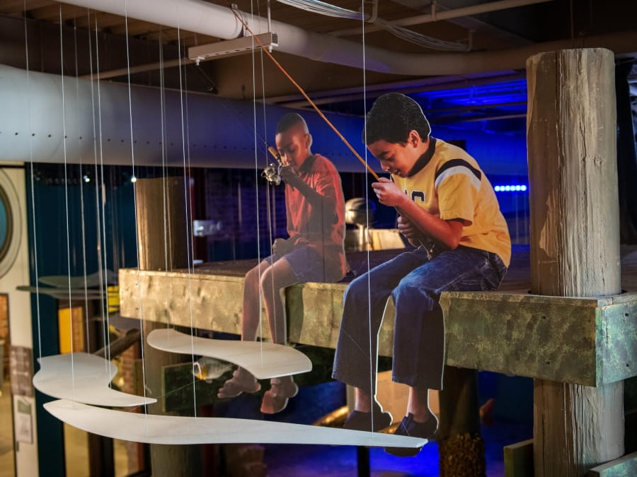 cardboard cutouts of boys fishing on ledge above OAC aquarium