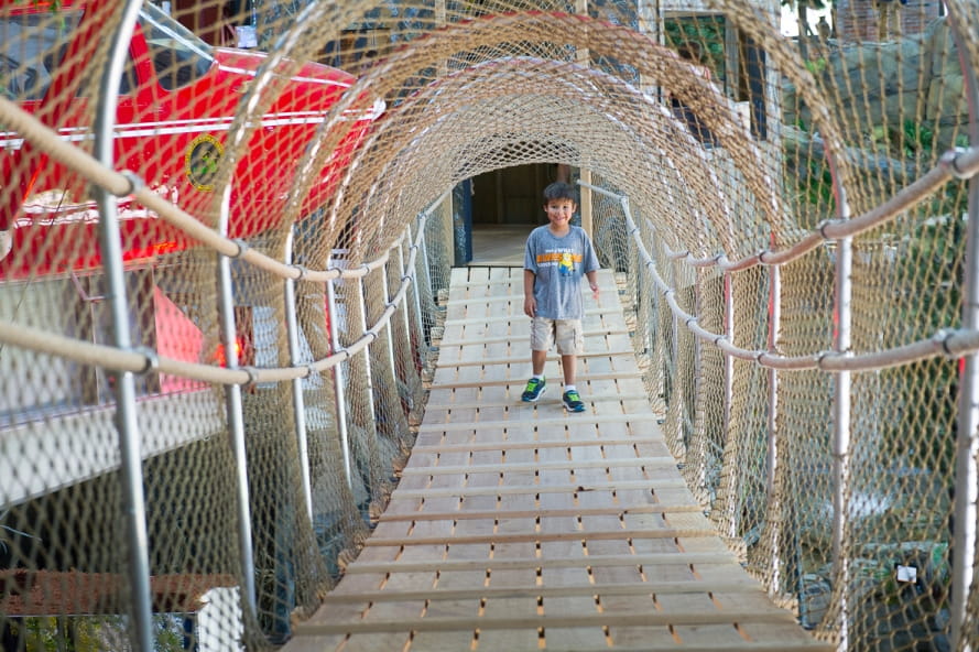 young boy standing on suspension bridge at the Outdoor Adventure Center