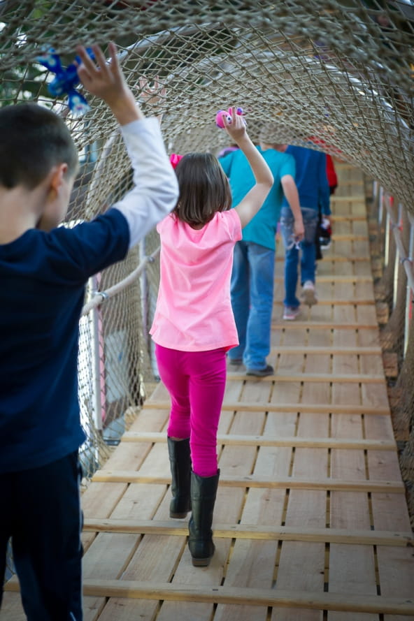 line of kids cross the suspension bridge at the Outdoor Adventure Center
