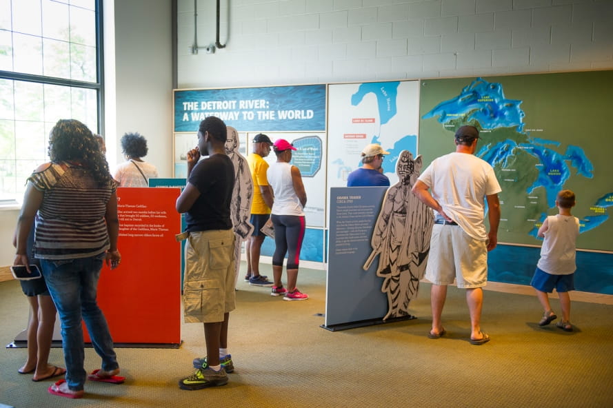 Visitors look at information about Detroit River history in Outdoor Adventure Center exhibit