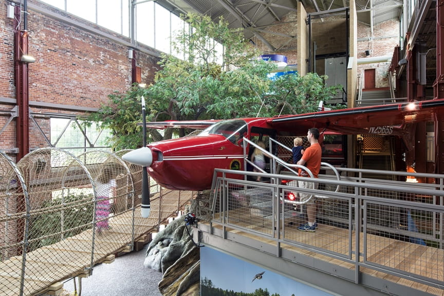 father and two young kids going inside airplane at Outdoor Adventure Center