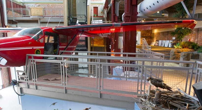 side view of red airplane at Outdoor Adventure Center and walkway leading to it