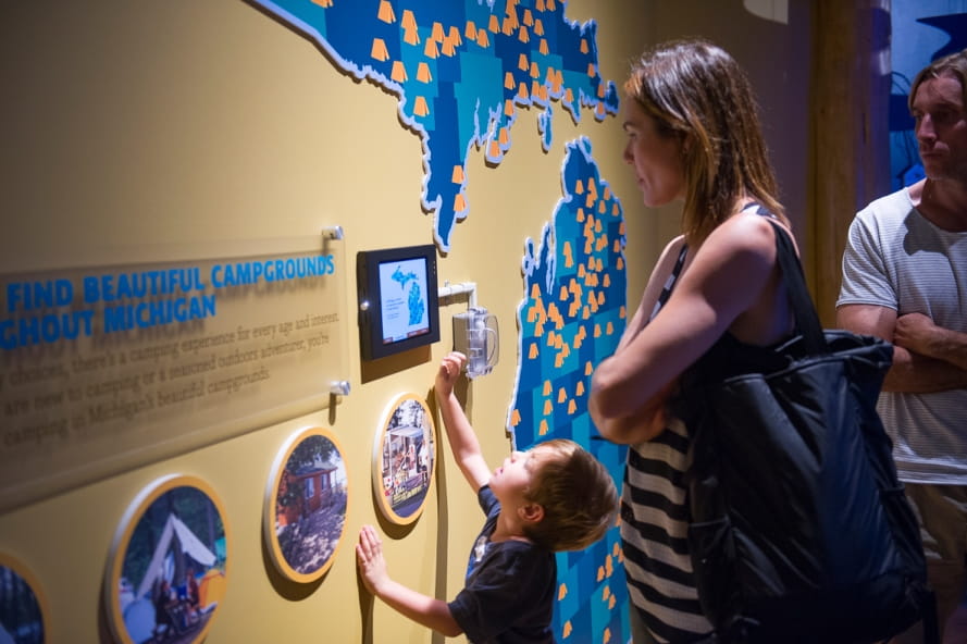 mom and son look at map and iPad with information about Michigan campgrounds at the OAC