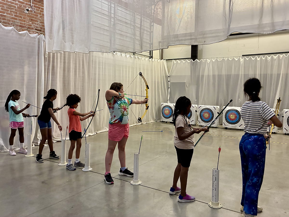 group of young people lined up to shoot at archery targets