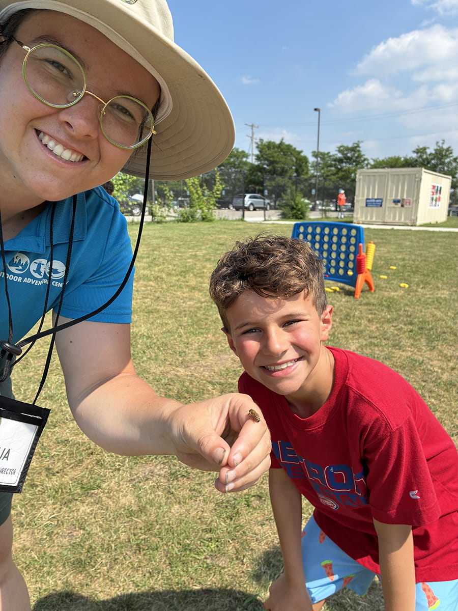 summer camp staffer with bee on hand while camper smiles