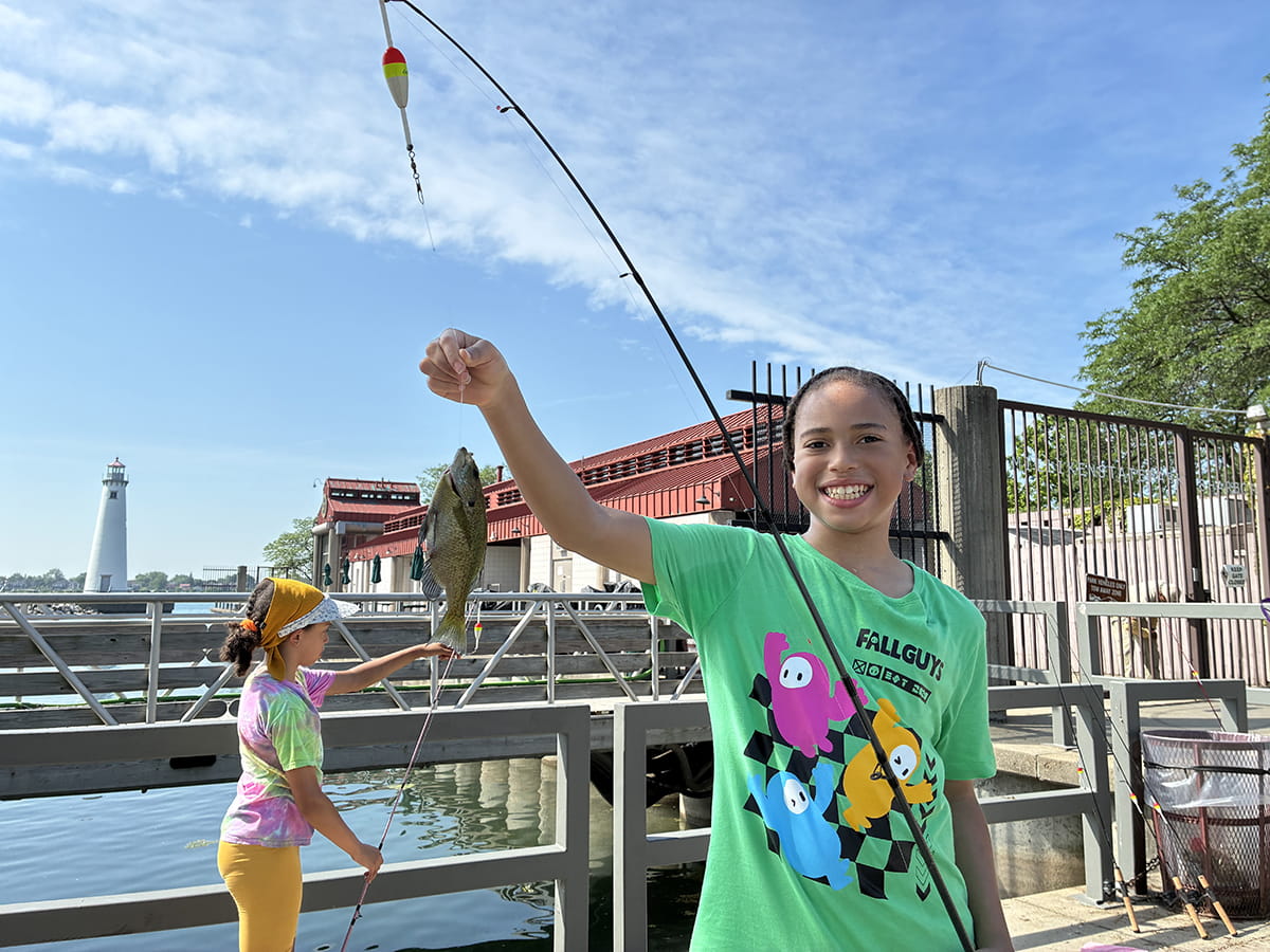 young person holds up a fish on a pole