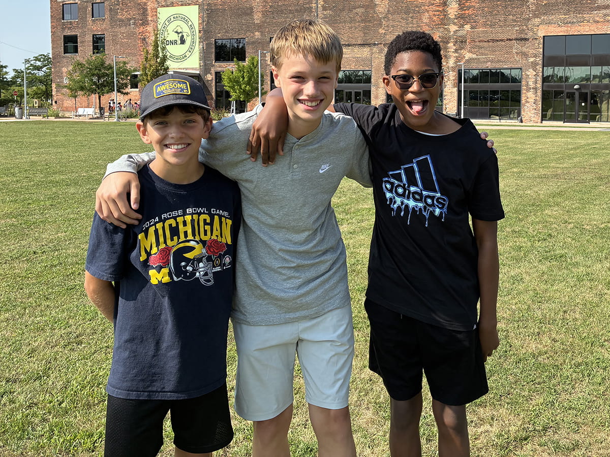 three summer camp attendees on Outdoor Adventure Center lawn