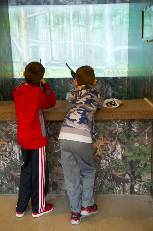 two boys try out the hunting simulator at the Outdoor Adventure Center