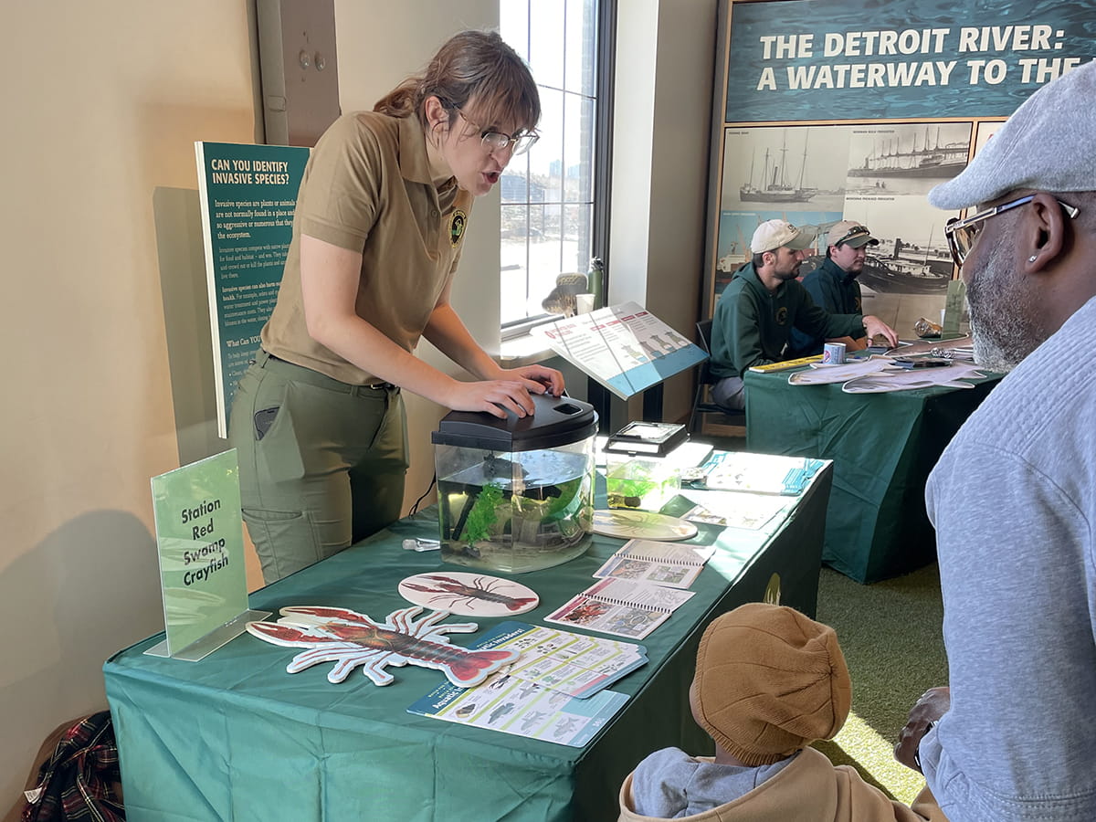 OAC staffer at display table talking to child and adult
