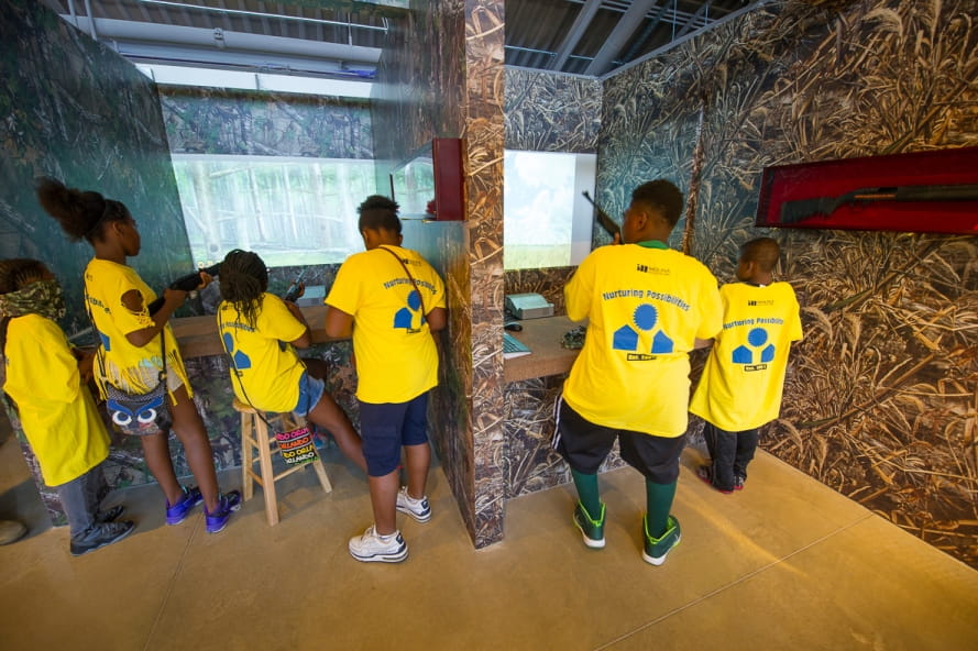 group of kids try out the hunting simulator at the Outdoor Adventure Center