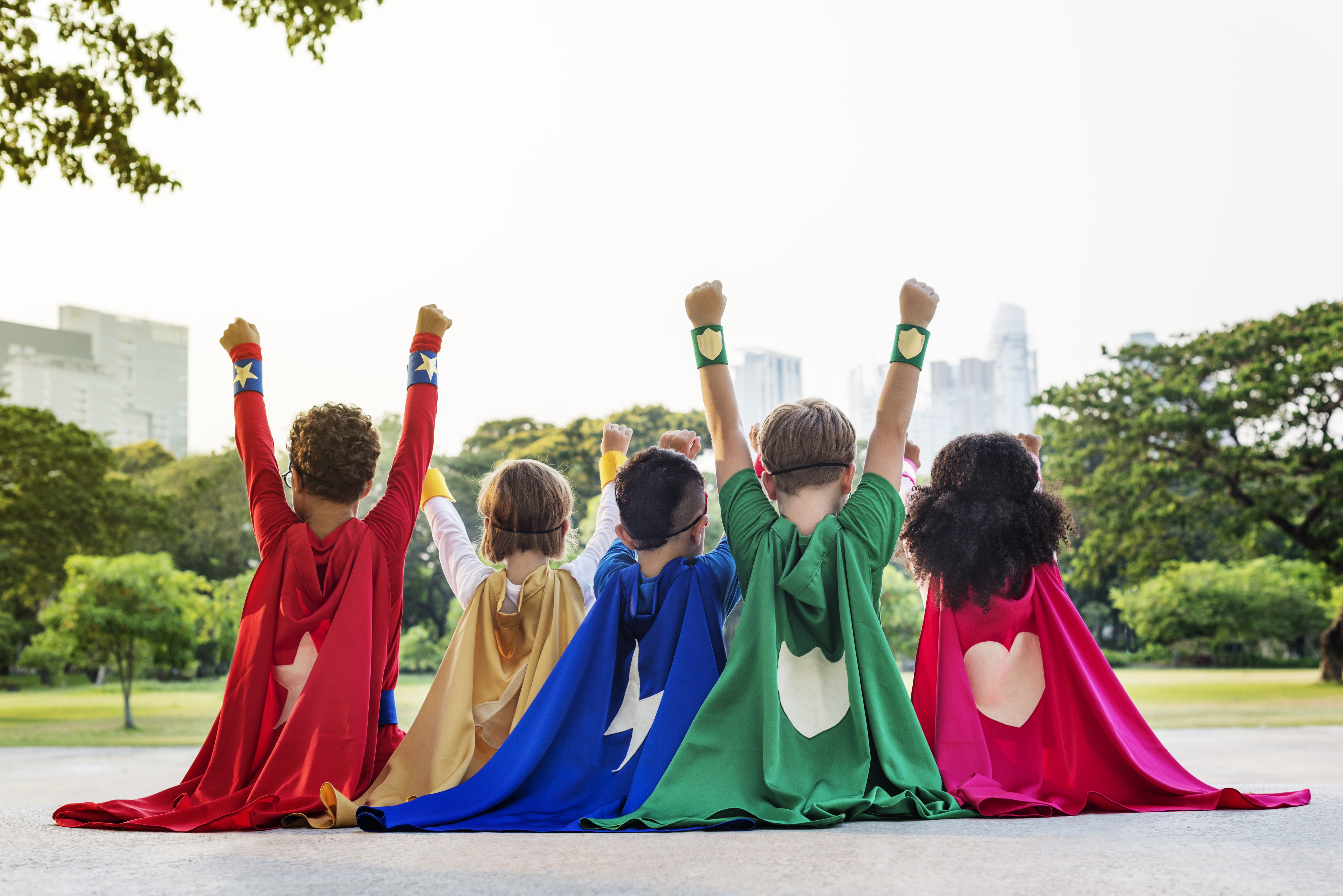 Children in superhero costumes sitting in a line. 