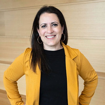 Gladys poses in black shirt and mustard blazer