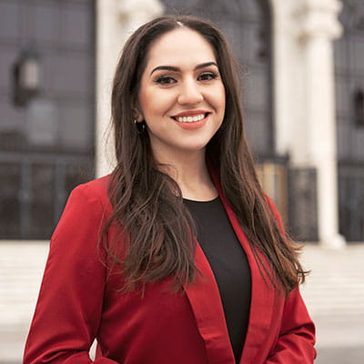 Veronica smiles wearing a black shirt and red blazer