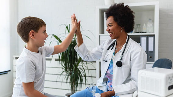 Female doctor high fiving young child in clinic