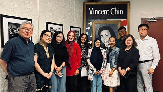 Ten commissioners posed in front of a portrait of Vincent Chin