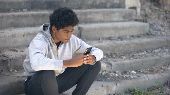 Young Black Boy upset - looking at mobile phone