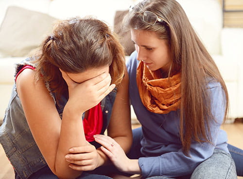 Sad girl being consulted by friend