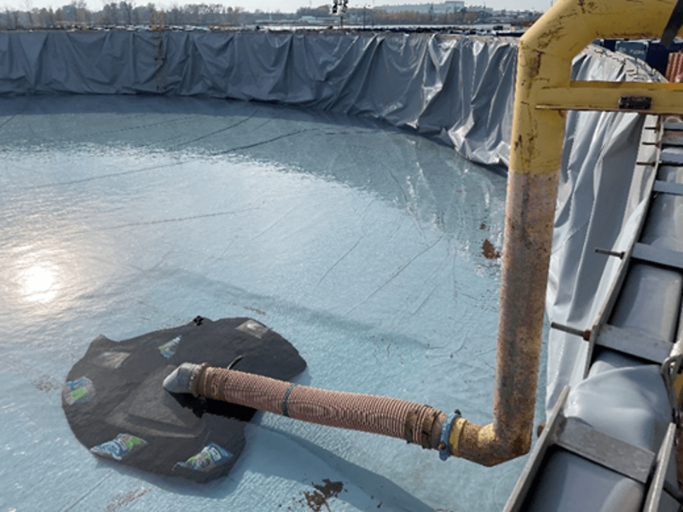 A large tank with a pipe going into it, the tank is holding treated water