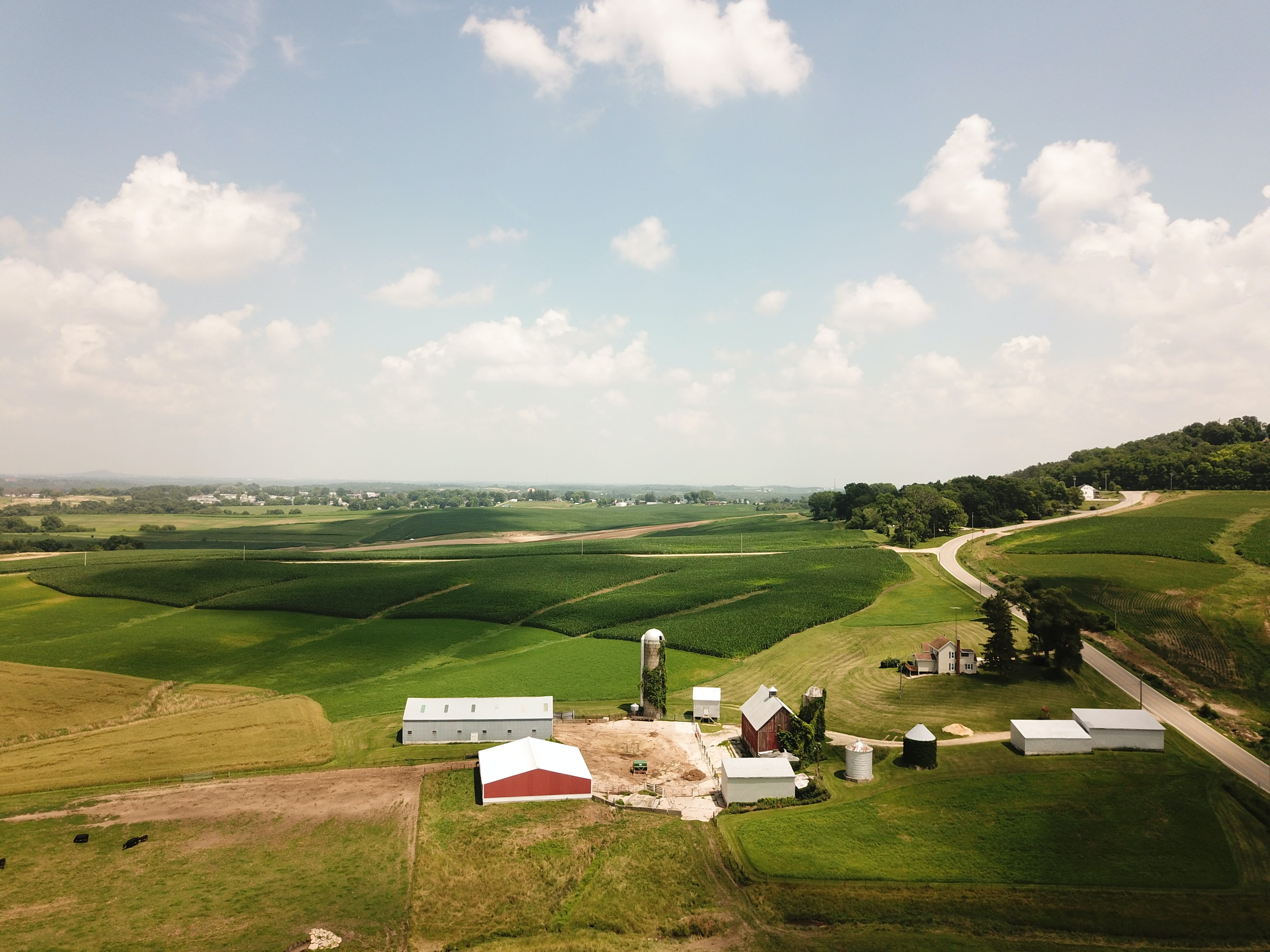 A farmhouse, red barn, and silos surrounded by farm fields