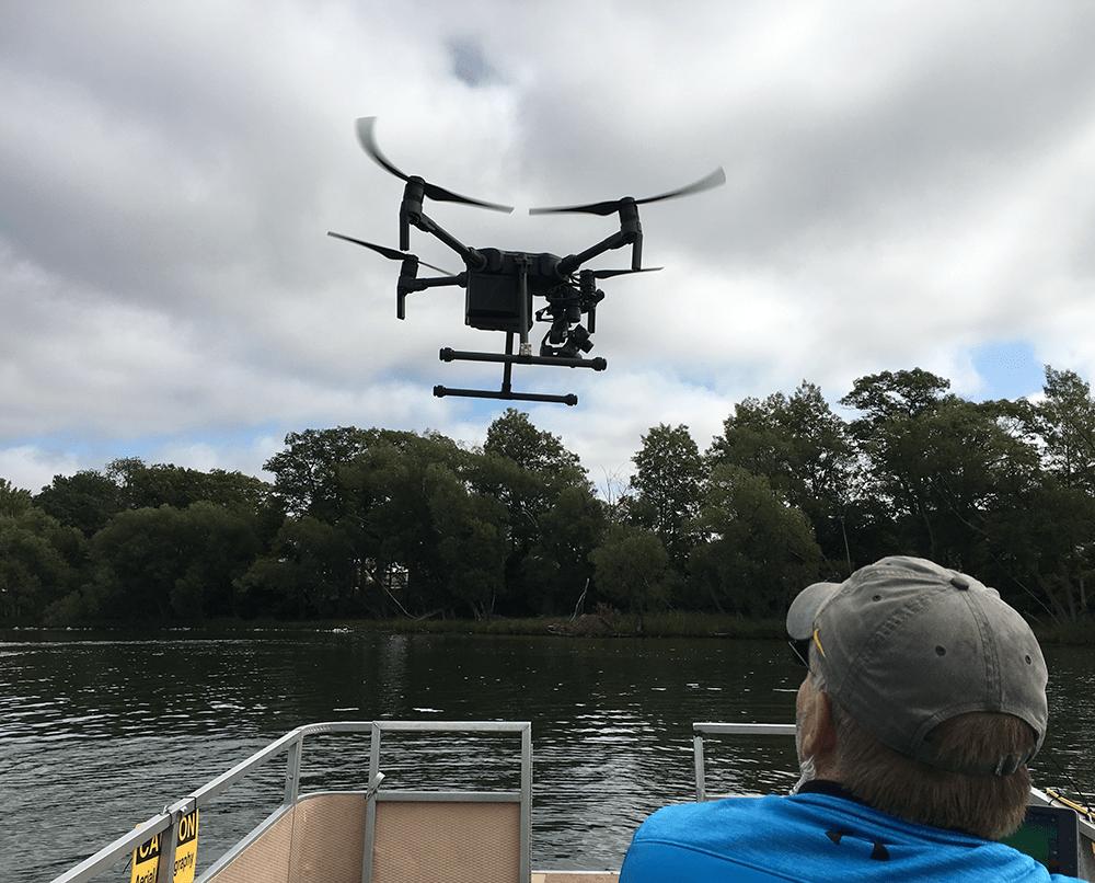 A drone lifting off of a boat over Lake Margrethe as an EGLE staff person looks on