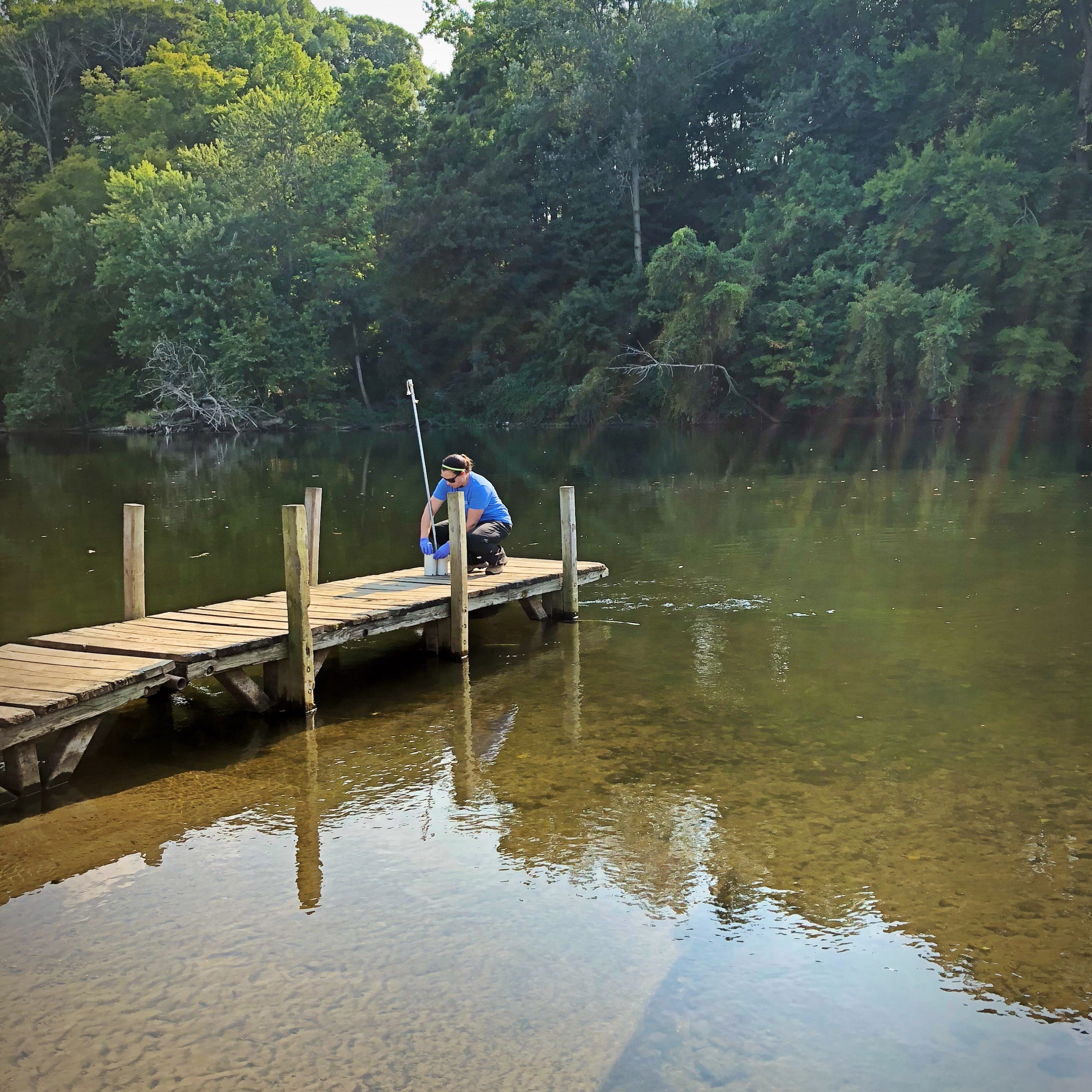A person standing on the edge of a dock into a lake
