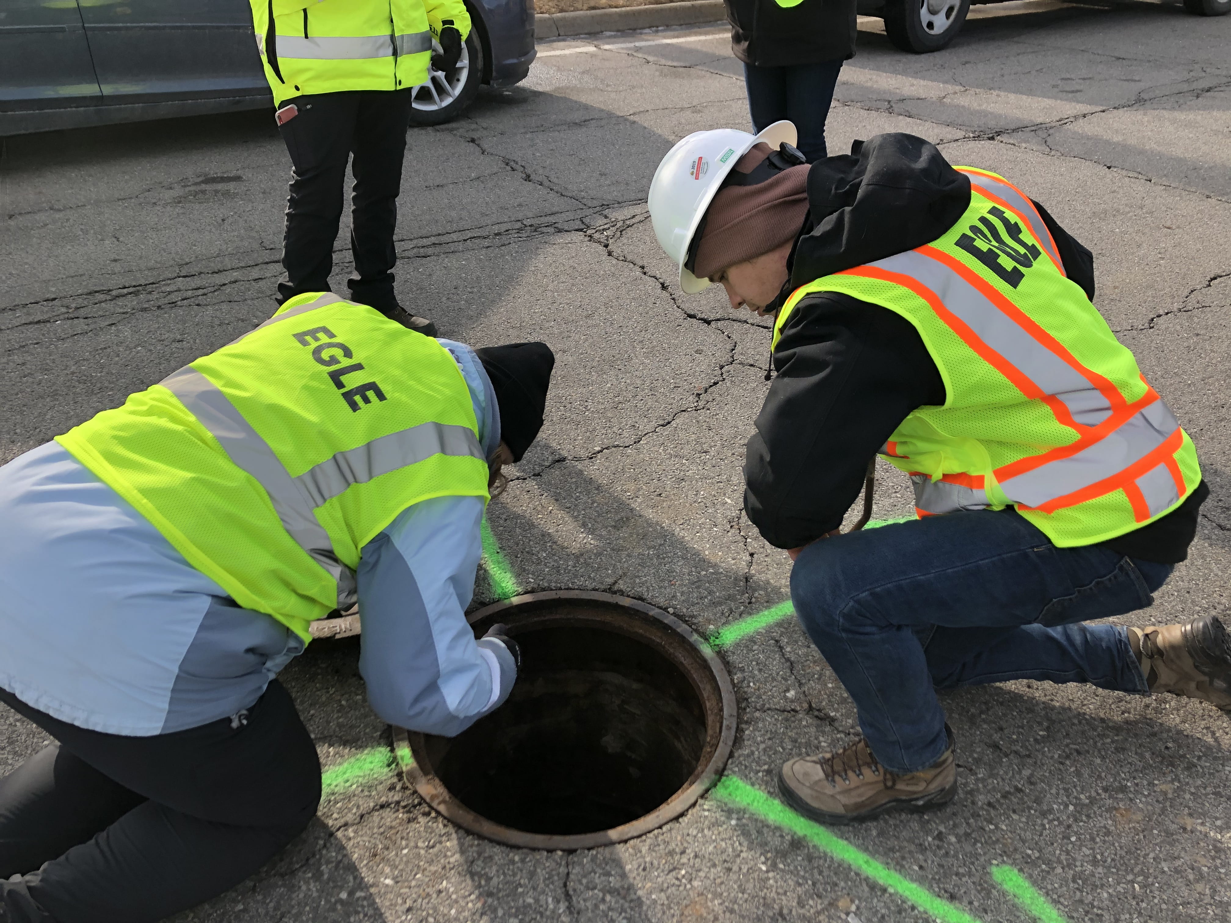 A group of EGLE staff looking into a roadside manhole as part of an inspection