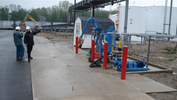 Two people conducting an industrial storm water inspection; looking at an outdoor pumping system.