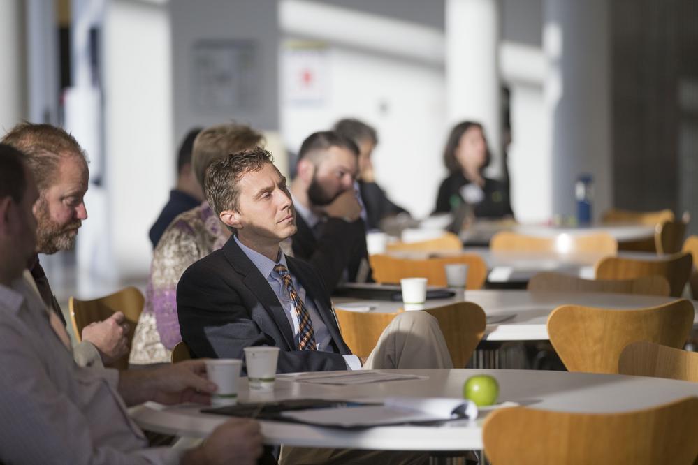 A man in the audience of a presentation, sitting back and listening
