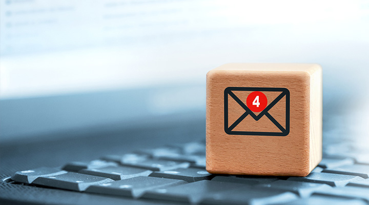 Wooden block on a laptop with an email icon that has alerts. 
