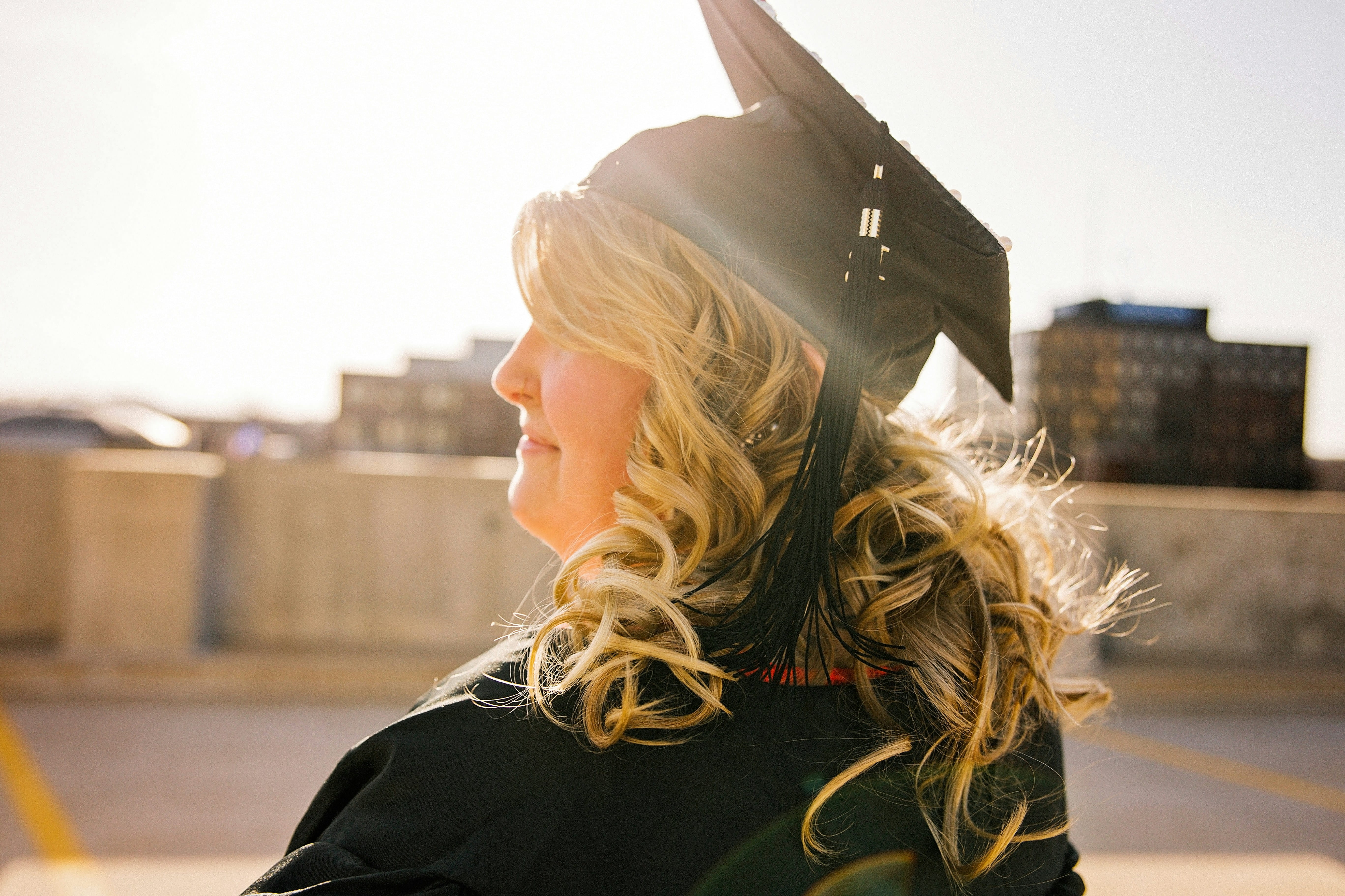 A graduate wearing that cap and gown with the sunset.