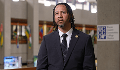 Man in a suit sitting in front of a camera for an interview