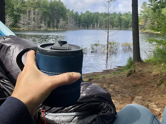 camper holding mug with lake in background