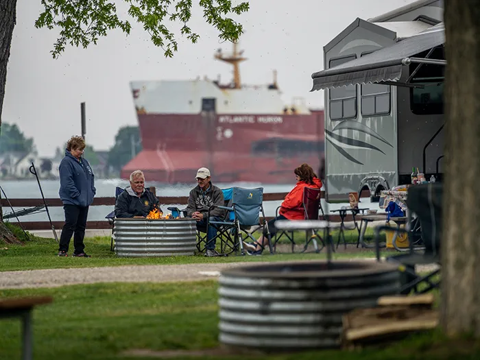 campers around campfire with freighter in background