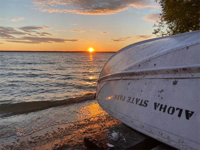 boat resting on shoreline with Aloha State Park written on side