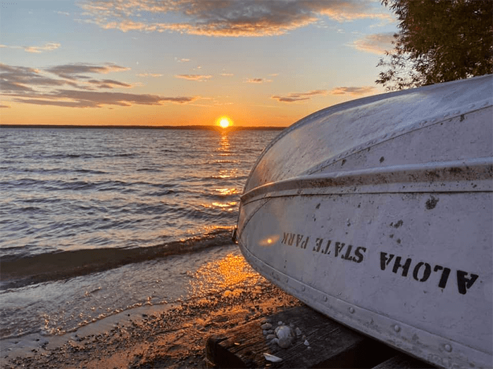boat resting on shoreline with Aloha State Park written on side